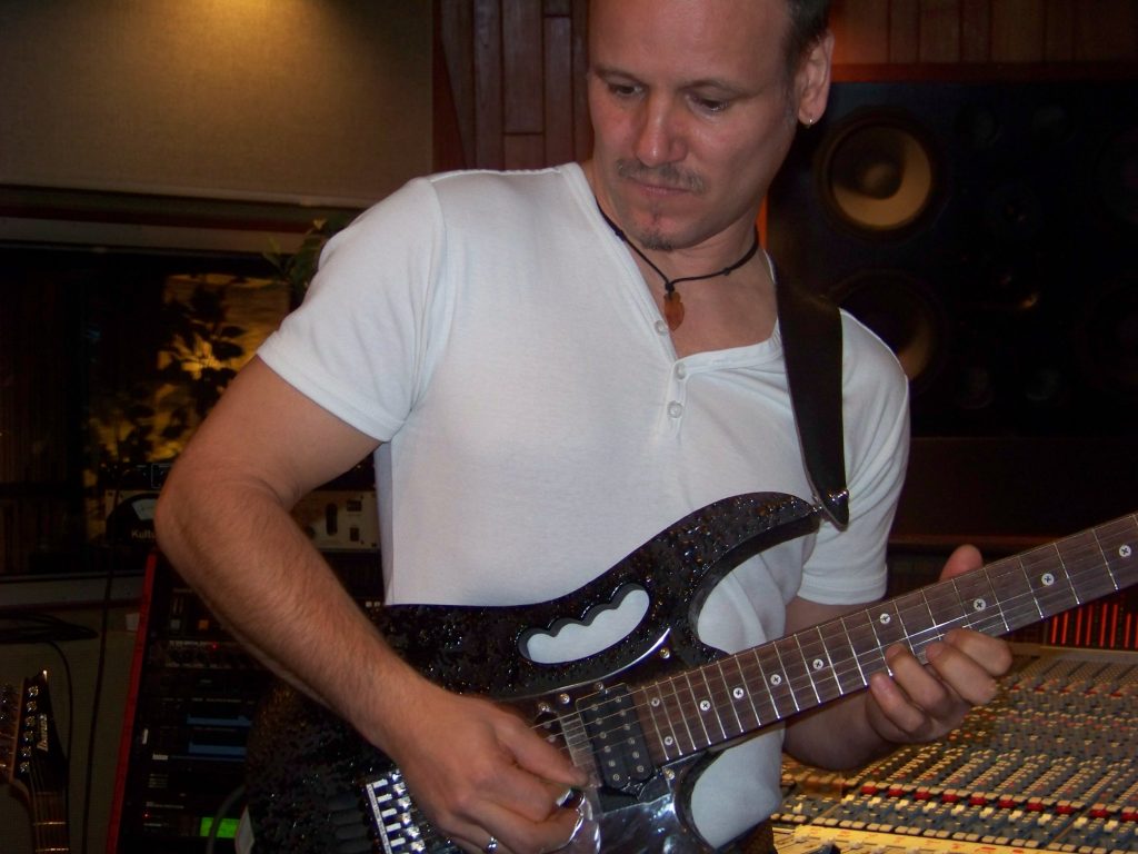 Porträt von Joey Krüger mit E-Gitarre im Tonstudio beim Einspielen eines Gitarrenparts