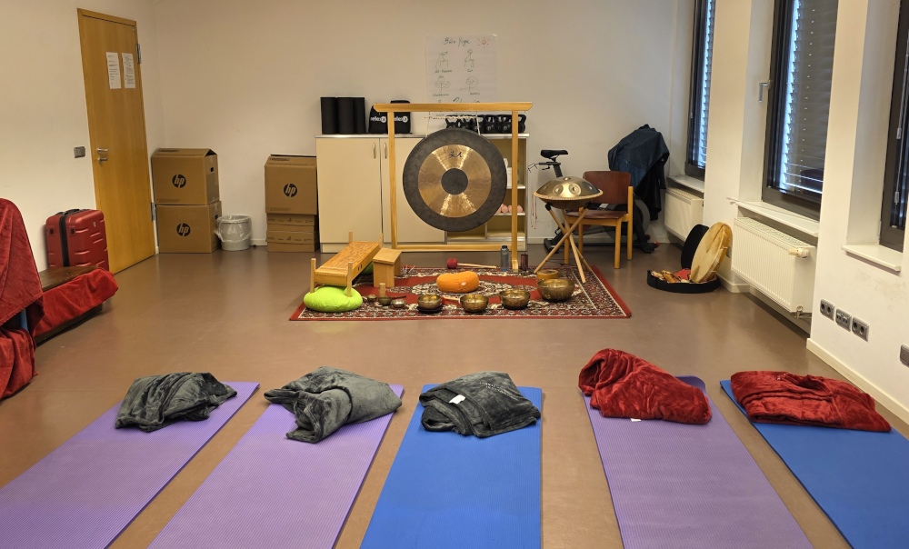 Schlichter Büroraum mit Yogamatten, Decken und Klanginstrumenten – Vorbereitung für eine Klangreise im Arbeitsumfeld