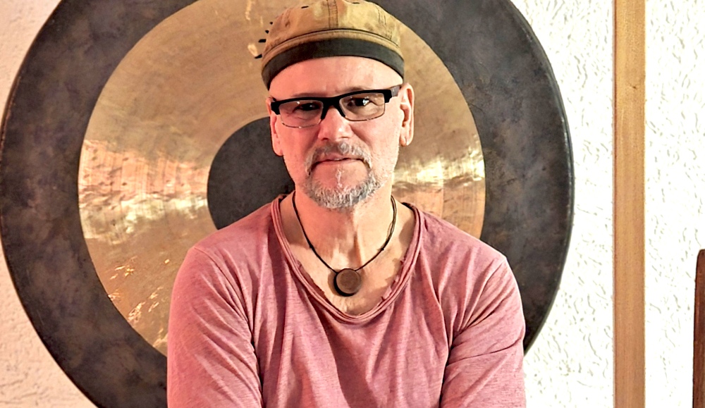 Joey Krüger sitzt ruhig vor einem großen Gong – Klangtherapeut und Klangkünstler aus Frankfurt Oder